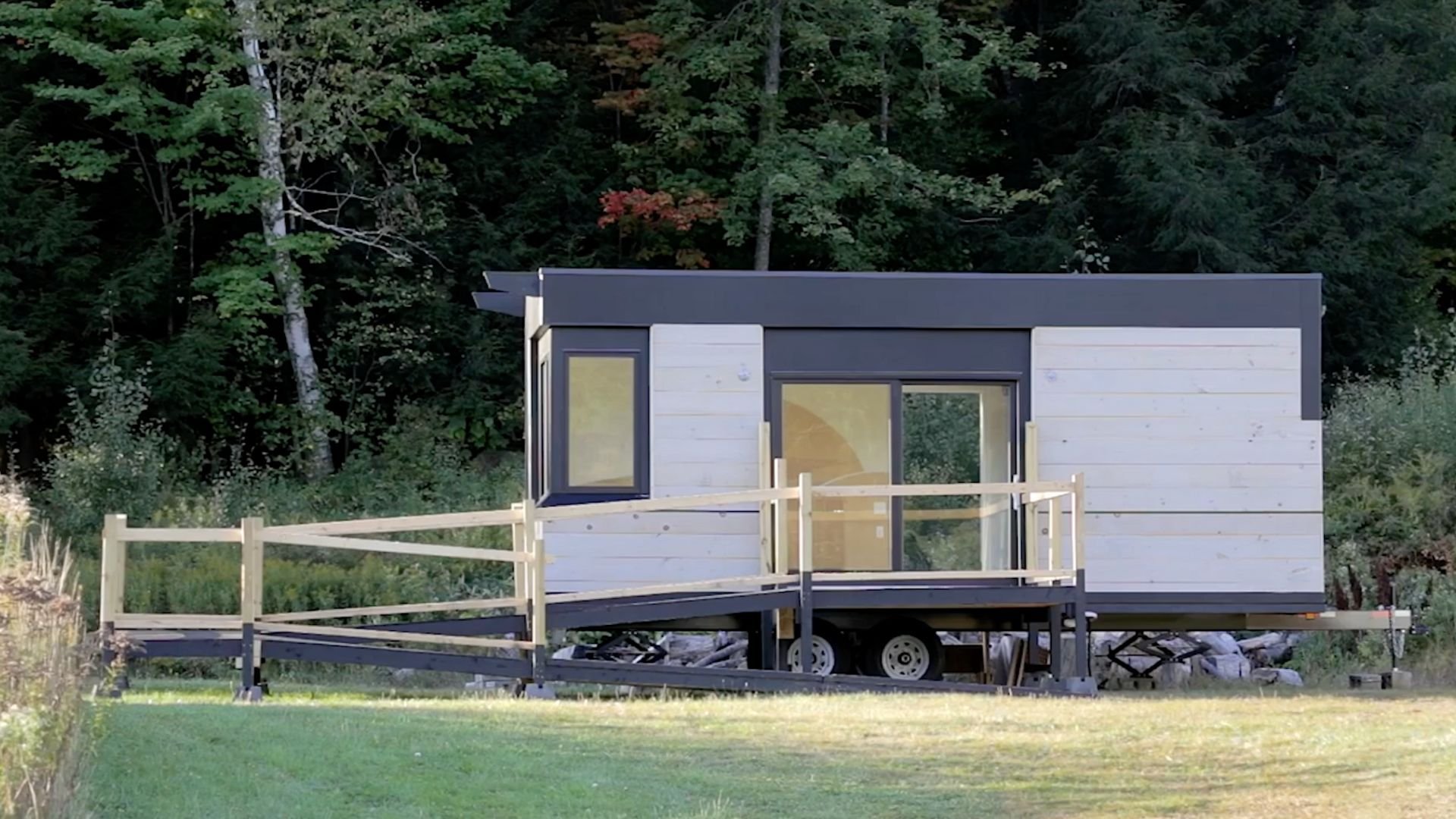 A SuitePAD with a wooden ramp attachment sits on its trailer in a field against a backdrop of a forrest.