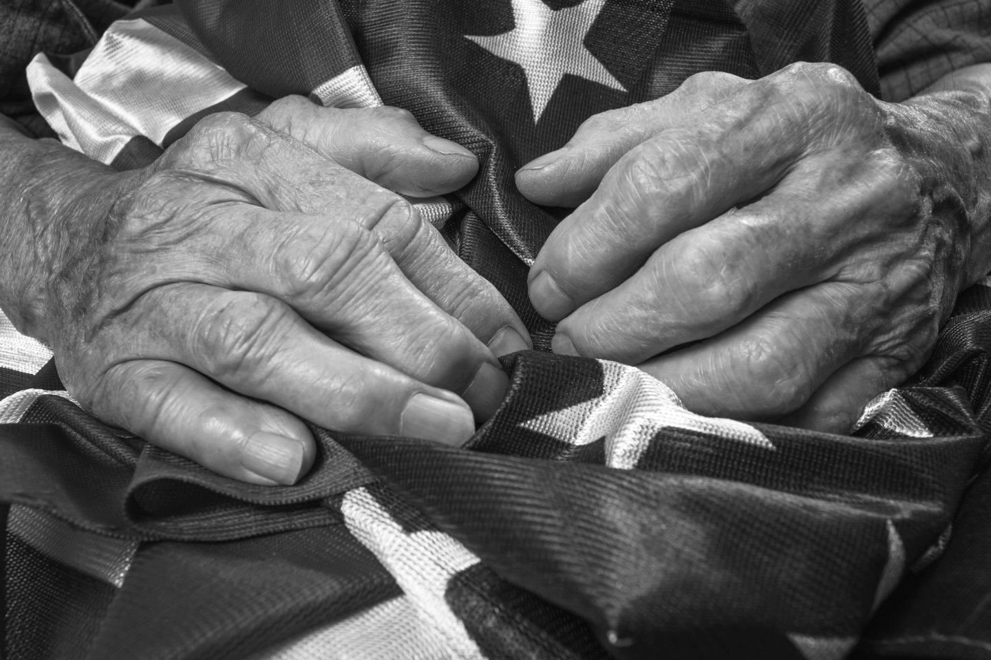 older person's hands holding an American flag